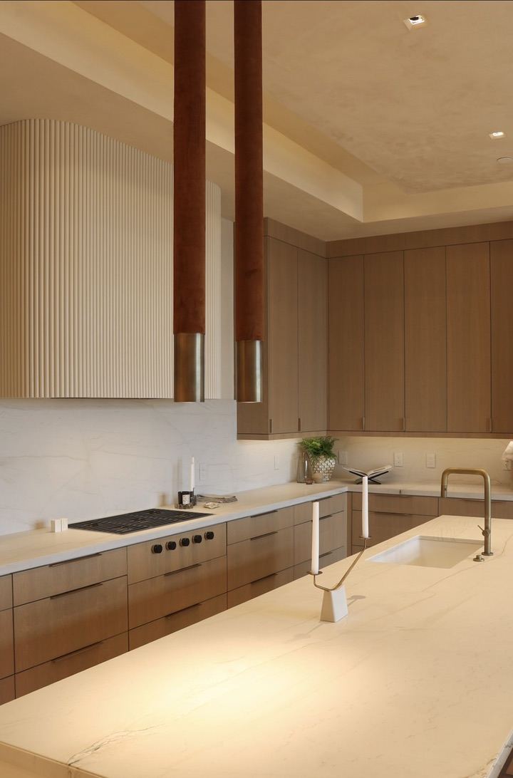 Kitchen detail with fluted range hood and brass pendants