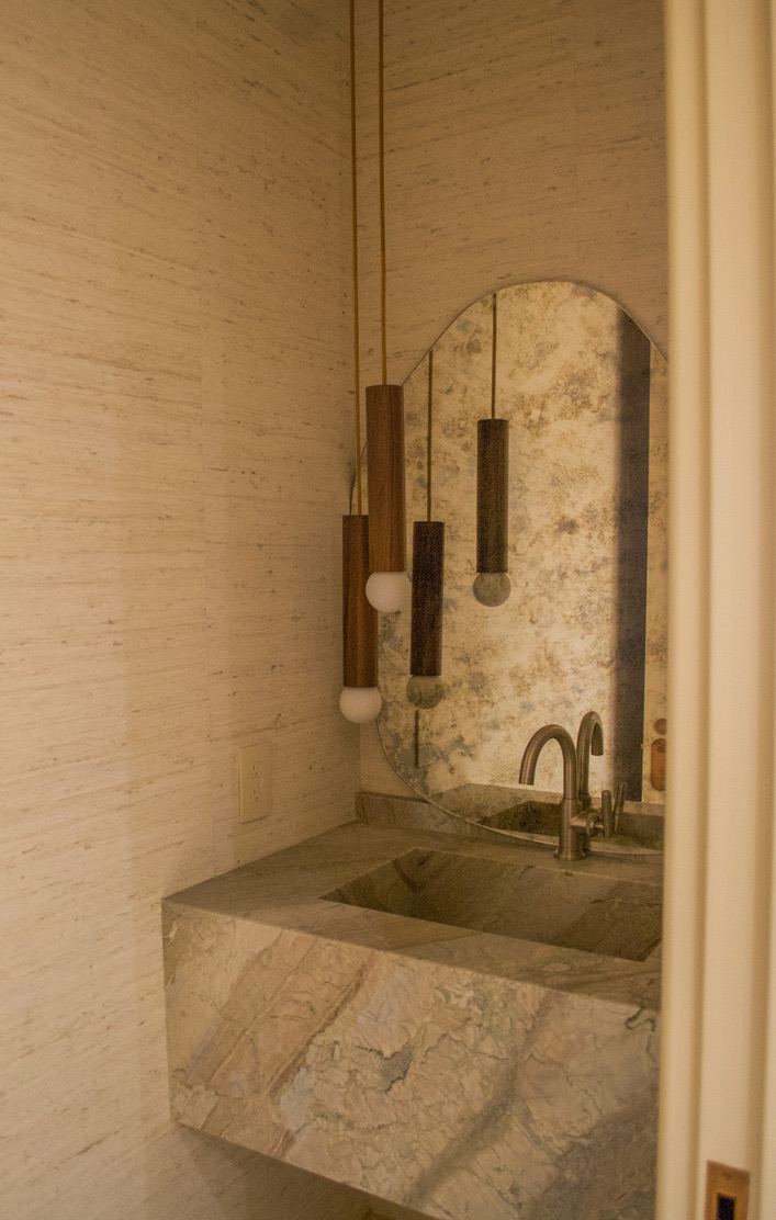 Powder room with stone vanity and arched mirror